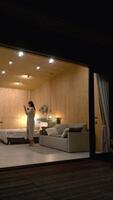 Elegant woman enjoys a glass of wine while dancing in her contemporary, minimalist hotel room at night, creating a peaceful and relaxing atmosphere video