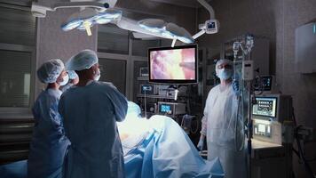 Medical professionals executing precise laparoscopic surgery with advanced technological equipment, showcasing collaborative expertise within modern sterile operating environment video