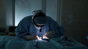 Professional surgeon meticulously performs a complex surgical procedure, illuminated by a focused light source, demonstrating precision and expertise in operating room video