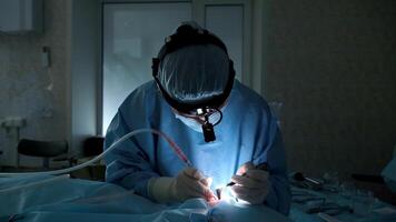 Professional surgeon meticulously performs a complex surgical procedure, illuminated by a focused light source, demonstrating precision and expertise in a sterile operating room environment video