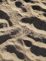 Footprints on Sandy Beach Closeup view of human footprints in soft beach sand lit by sunlight perfect for themes of travel solitude nature memory and storytelling in visual and editorial design photo