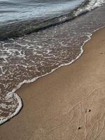 Golden sand surface with deep human footprints in warm sunlight showing beach texture and natural pattern photo