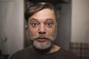 A man with facial hair is making a funny face in a portrait photo