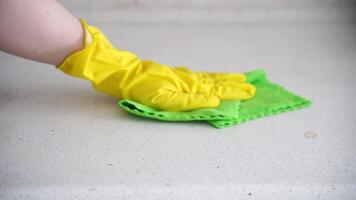 Cleaning process with gloved hand using green cloth on white surface in threestep sequence. video