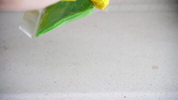 Cleaning process on white surface with bright green cloth and yellow gloves in smooth motion sequence. video