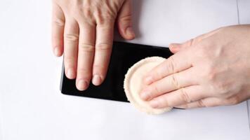 Caucasian female cleaning smartphone screen with cloth in three progressive steps for device maintenance. video