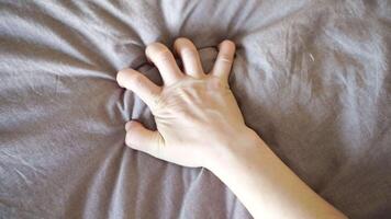 Caucasian female hand gripping gray fabric in sequence showing tension and release gesture. video
