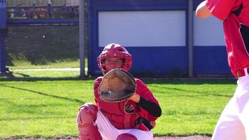 A young baseball catcher is fully engaged in action while playing competitively on the field video