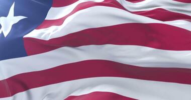 Flag of Liberia waving at wind with blue sky in slow, loop video