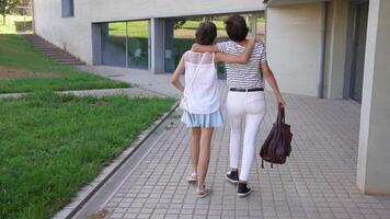 Two close friends enjoy a leisurely walk in a vibrant, modern setting with greenery video