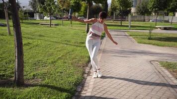 A Playful Young Woman Joyfully Balancing on a Pathway in a Beautiful Sunny Park Setting video