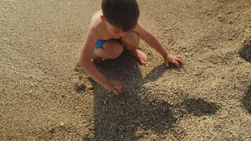 Summertime. Little child plays with sand on seaside beach in summer video