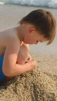 Vertical . Summer resort, family vacation. Small child playing with sand on seashore video