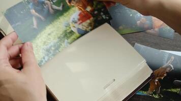 Father day concept. Hands inserting printed photo into picture album. In the photo happy son and father in summer video