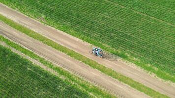 Aerial view of a cyclist on a bicycle riding on a country road between green fields. Cycling traveler riding across the field on a dirt road. photo
