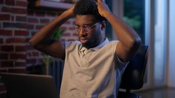 African American business man in night office overwork stress laptop problem online working deadline failure error trouble computer upset disappointed frustrated employee designer difficult task think video