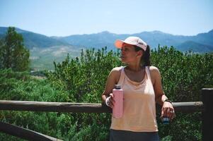 Athletic Woman in Outdoor Setting with Water Bottle and Scenic Mountain Views photo