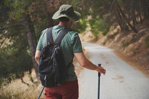 Traveler Exploring a Serene Forest Trail With Backpack and Walking Sticks photo