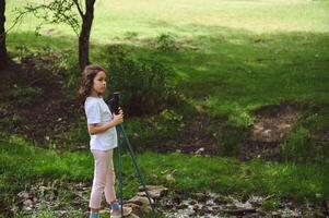 Young Girl Exploring Nature with Poles in Scenic Countryside Setting photo