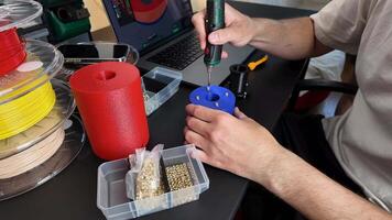 A person uses a 3D printer tool for DIY crafting, surrounded by filament spools and electronic components, showcasing innovation and creativity video