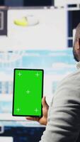 Vertical Entrepreneur looks at tablet with chroma key for analysis, reviewing monthly reports and infographics for company development. Good performance metrics for growth, forecasting. Camera A. video