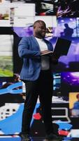 Vertical Black social media manager browsing high tech environment with app interfaces, infographics and social networking feeds. Big data on social media platforms, multimedia. Camera A. video