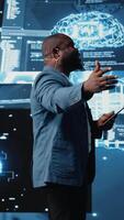 Vertical African american male specialist presenting deep learning AI systems, ensuring robotics for automation and neural networks brain innovation. Young professional presenter host. Camera A. video