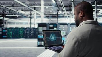 Software developer in data center uses AI technology on laptop to optimize storage volumes. IT expert in server hub facility using artificial intelligence to ensure seamless operations, camera A video