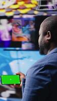 Vertical African american user holding a phone with isolated mockup display, digital system of networks and apps on dashboard. Highlighting the integration of AI and fintech. Multitasking. Camera A. video