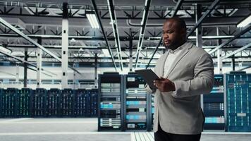 IT expert in industrial data center analyzing infrastructure performance, minimizing downtime and equipment failure risks. Server farm worker doing job tasks, automating anomaly detection, camera A video