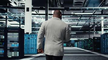 Data center technician using laptop to manage software updates for system stability. African american server room IT professional optimizing performance, configuring infrastructure, camera A video