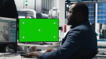 Male tech specialist reviewing assembly line next to mockup on pc, manages factory operations in solar power plant to ensure effective quality control and commitment for green energy. Camera A. video