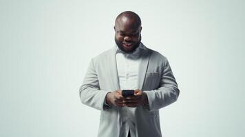 Smiling man using phone gains access to thousands of videos with press of a button. Jolly african american man enjoys free time browsing favorite online clips on smartphone, camera A