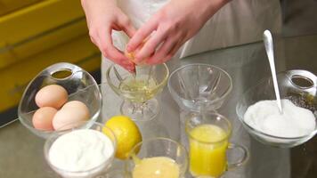 Chef puts separate whole egg yolk into glass bowl close up. Food , promotion, marketing, restaurante. Preparing desserts at home video