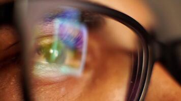 a Macro closeup of eyes with eyeglasses looking at phone video