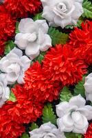fragment of funeral wreath, red and white artificial flowers as background, close up photo