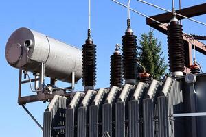 High-voltage insulators and electrical components of a power substation outdoors, surrounded by trees. Industrial electricity distribution infrastructure. photo
