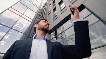 Middle-aged Caucasian business man confused with mobile phone trouble near office building lost signal loosing Wi-Fi connection problem in city businessman male searching connect online chatting app video