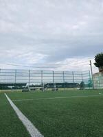 Soccer field with green turf and cloudy sky in afternoon photo