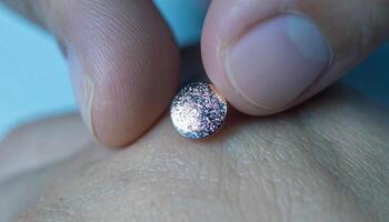 A person holding a small pink diamond on their finger photo