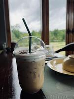 A iced coffee with a straw sitting on a table photo