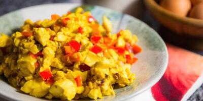 Scrambled eggs with diced red peppers served on a decorative plate, ready to be eaten. photo