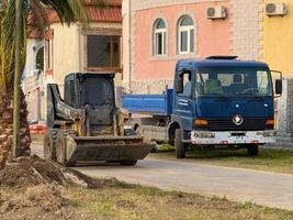 Skid-Steer Loader Dumping Soil into Truck at Urban Worksite photo