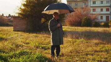 Man Standing Still Under the Sun Rays with an Open Umbrella video