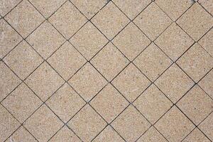 Tiles of stone chips cover the surface of the ground in the city. Green sprouts sprout through the tiles. Abstract background. photo