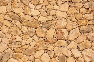 Natural stone wall texture in Spain with warm tones and varied shapes enhances the rustic charm of the landscape photo