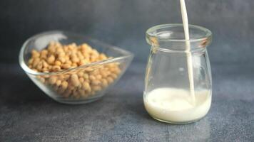 Pouring soya milk into a jar next to a bowl of soya beans video