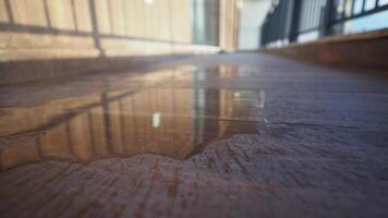 Water puddle reflecting light on wooden surface video