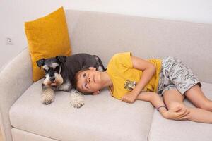 Children enjoy playtime with a dog on a cozy sofa at home during the afternoon photo