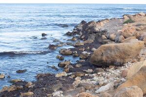 Explore the serene coastal landscape of Spain with rocky shores and calm ocean waves under a clear sky photo